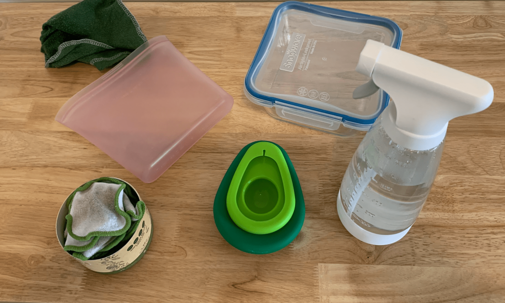An assortment of eco friendly products such as a spray bottle, cotton pads, and avocado huggers.